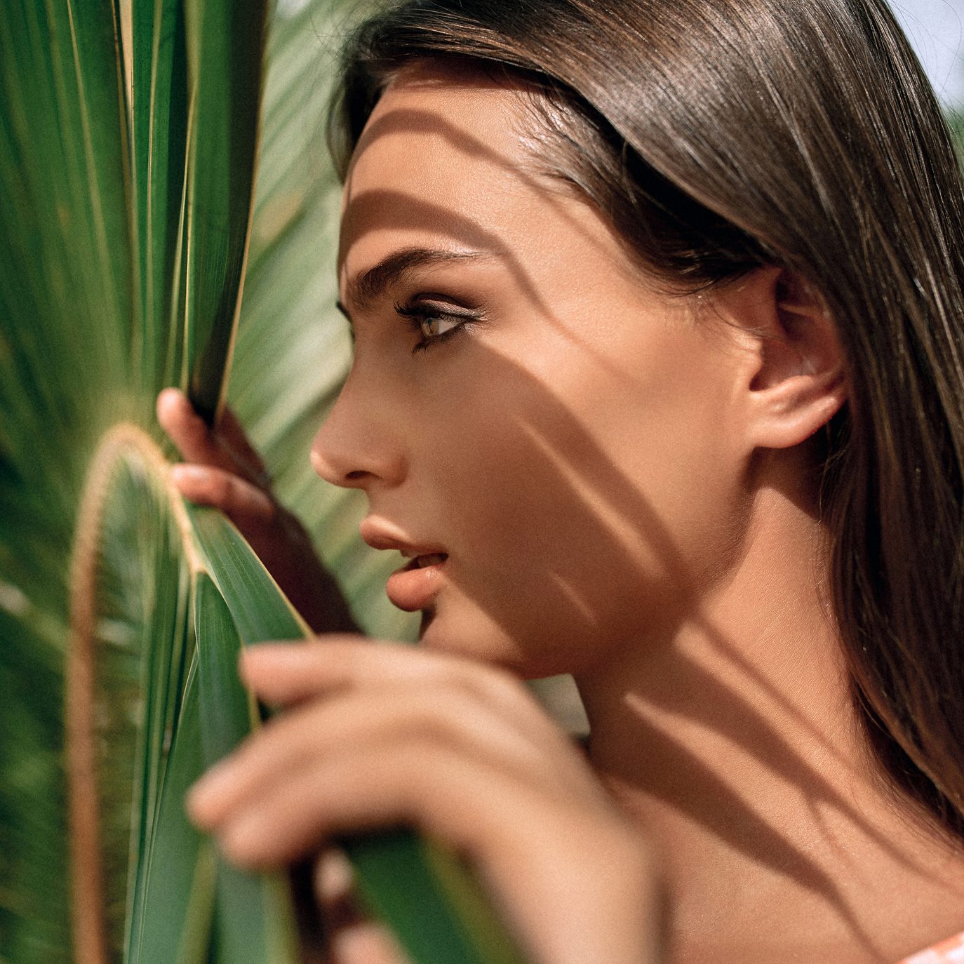 Aesthetic Mentorship Circle for injectors — woman in profile with glowing skin in palm-leaf shadow