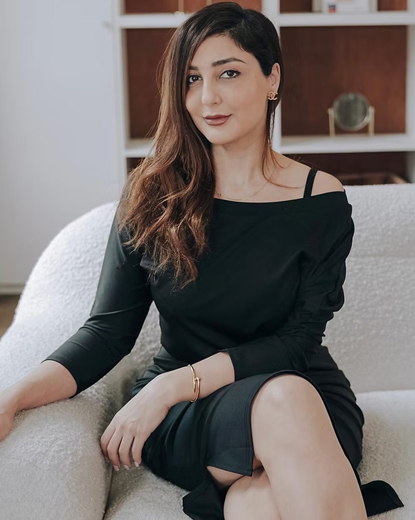 Dr. Aida Owlia, aesthetic medicine physician and injector trainer, seated in a cream armchair