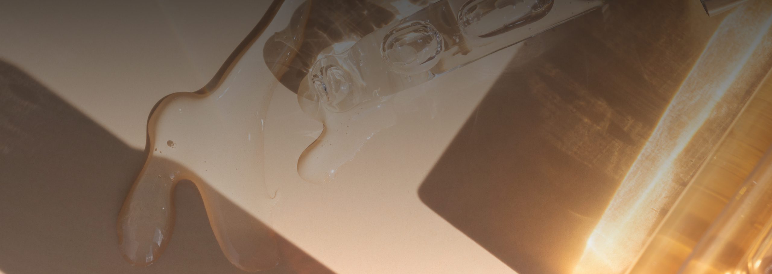 Book an aesthetic consultation at Dr. Owlia Aesthetics — golden serum textures in warm light