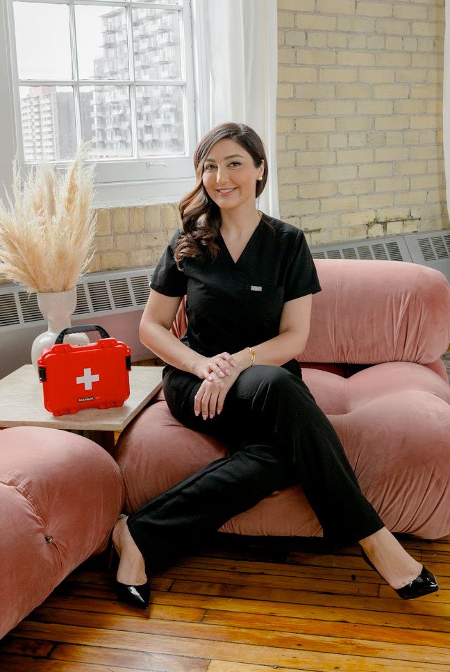 Dr. Aida Owlia, author of The Aesthetic Complications Manual, seated beside a red emergency kit