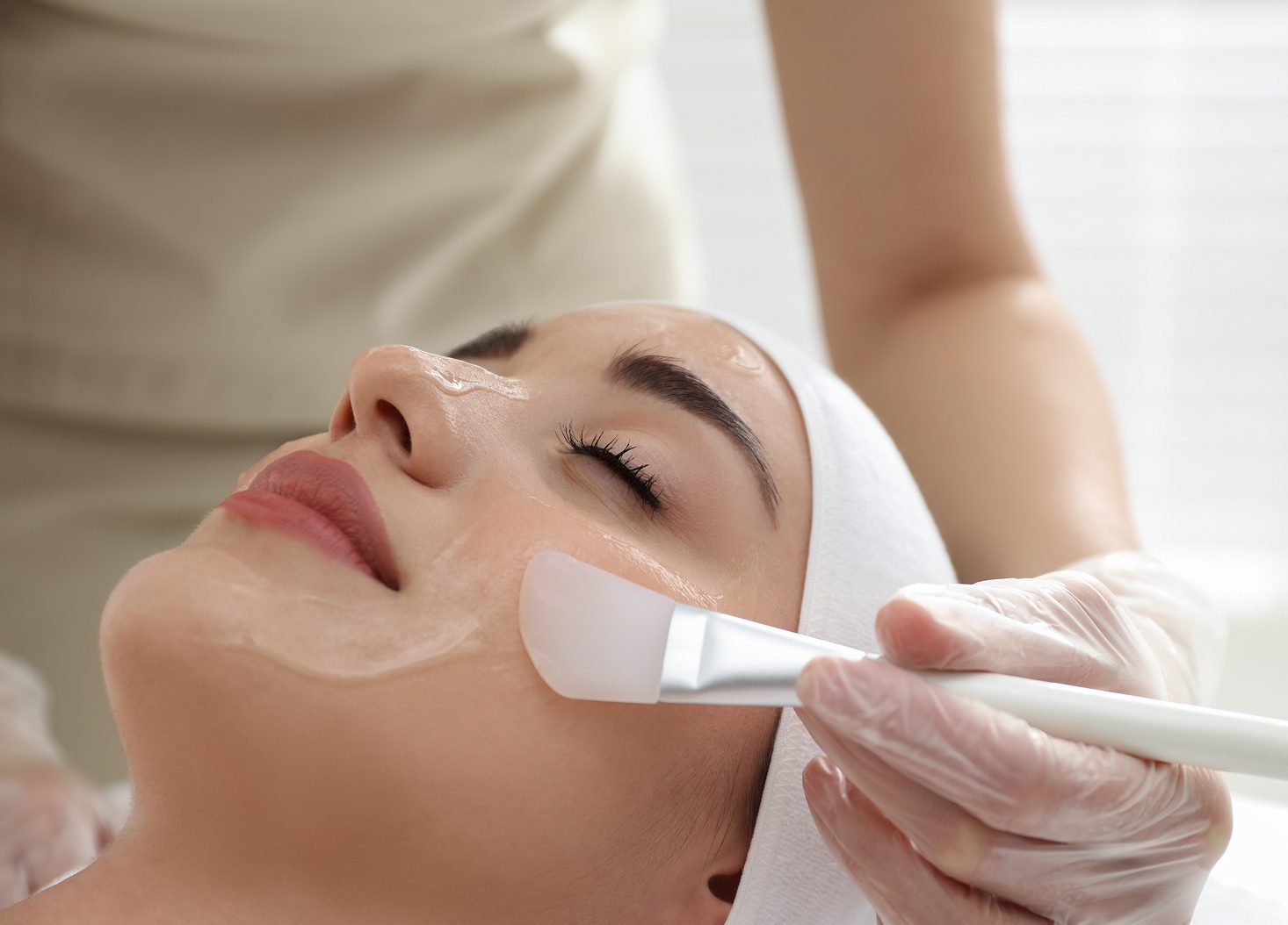 Professional care for treatment models — practitioner brushing a treatment mask onto a client's face